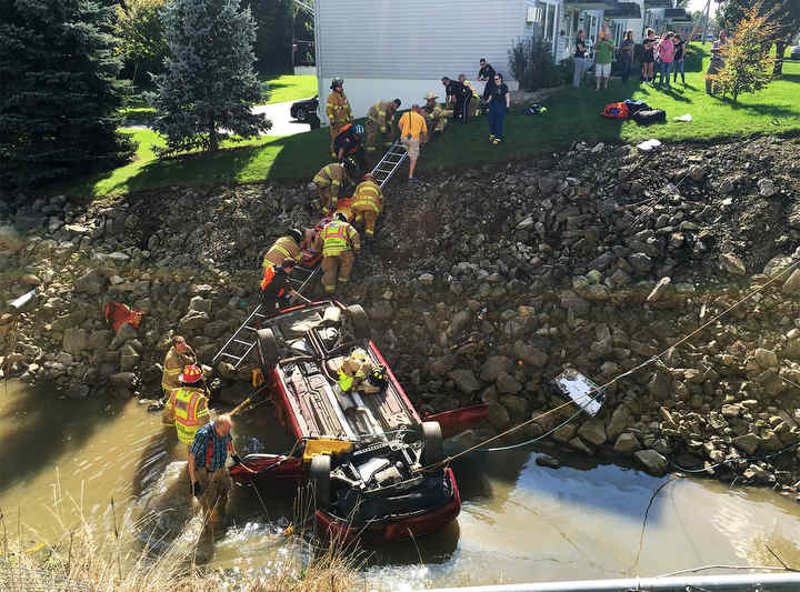 An unidentified man is slid up an embankment on a backboard after he was injured when his car rolled down and overturned into Sucker Run Creek near W. Maple Street just west of Race Street in Clyde.  (Molly Corfman / The News-Messenger)